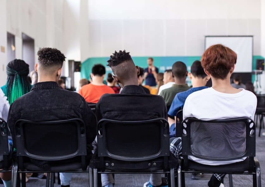 Three male students sitting in back of classroom