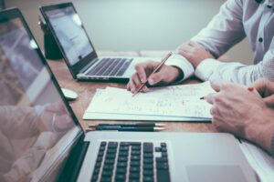 Actuary working with pencil and paper and laptop at desk