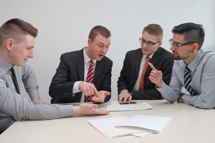 “Four students sitting at a table, discussing and debating”