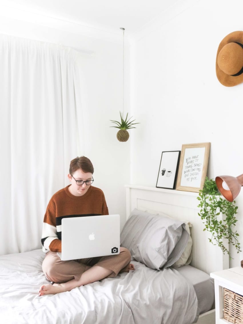 Student on laptop sitting on bed