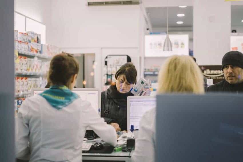 Pharmacists behind a computer servicing patients