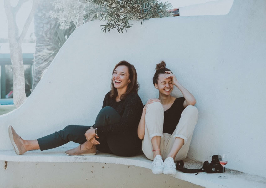 These two girls are enjoying getting to know each other as they chat on a bench on campus.