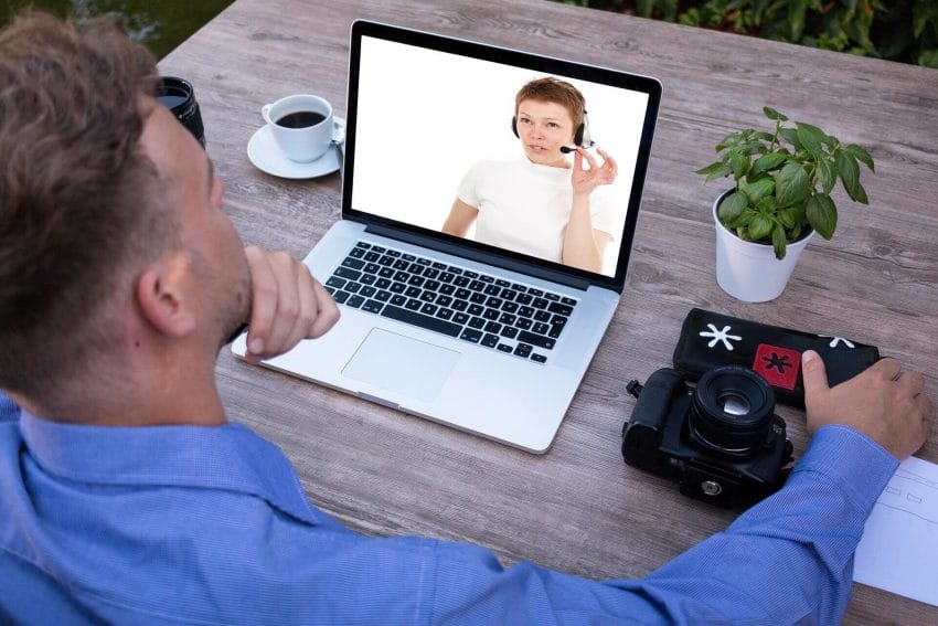 Man on laptop watching a woman on the screen teaching with a headset