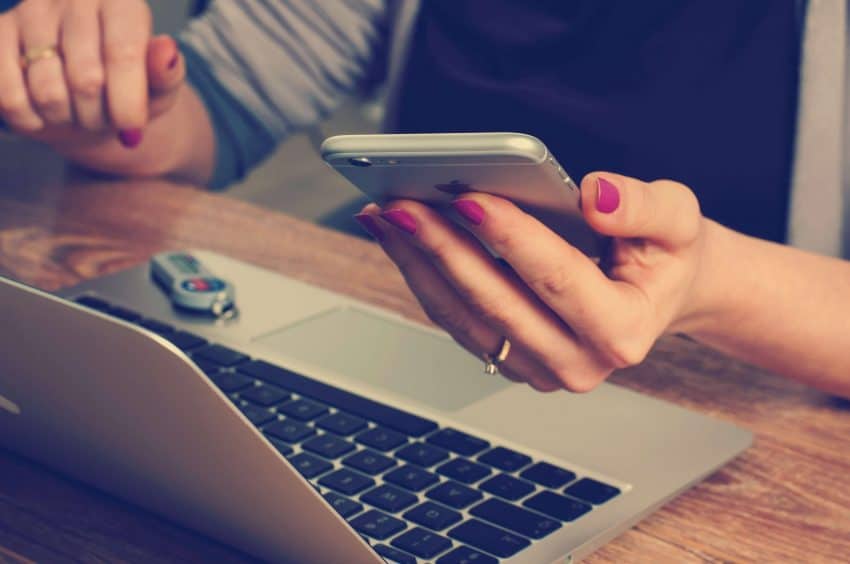 Teacher using cell phone and laptop on table