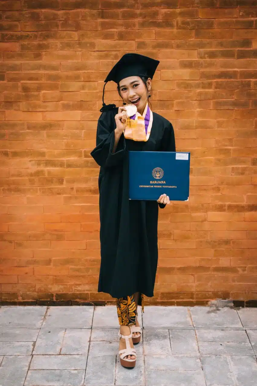 An excited graduate of bakery science poses with some bread and her diploma.