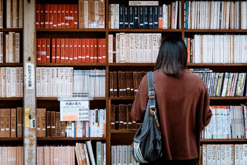 A high school student at her local library looking for reliable sources through books.