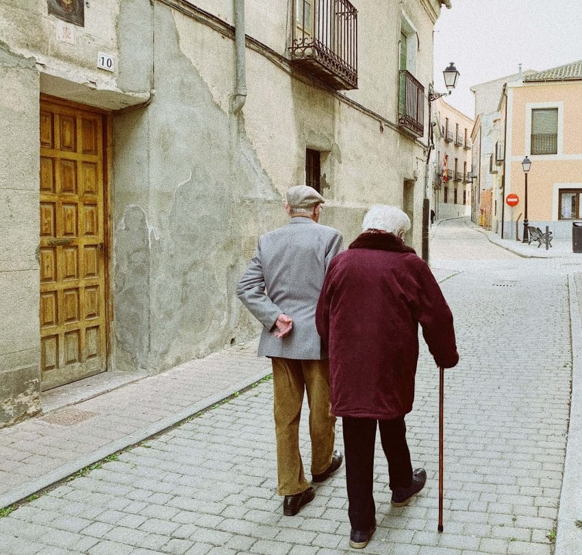 An elderly couple walking on a cobblestone street