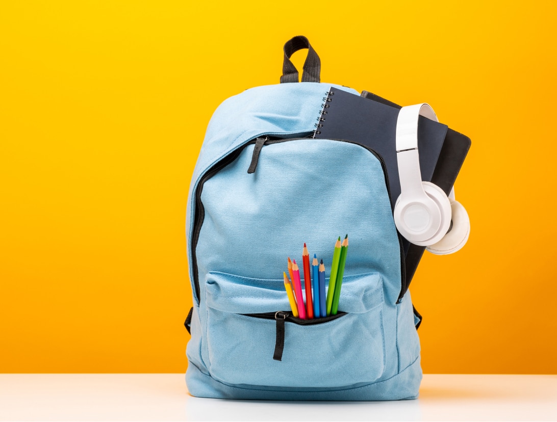 bag with pencils, headset, books with yellow background
