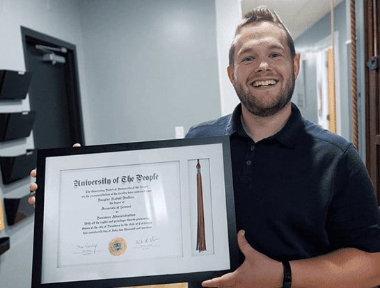 Doug Scaled holding certificate of University of the People