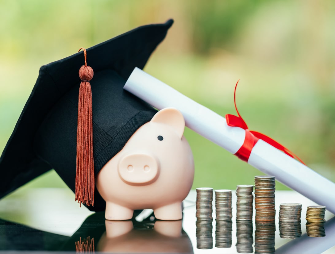 Piggy bank with toga hat, diploma and coins