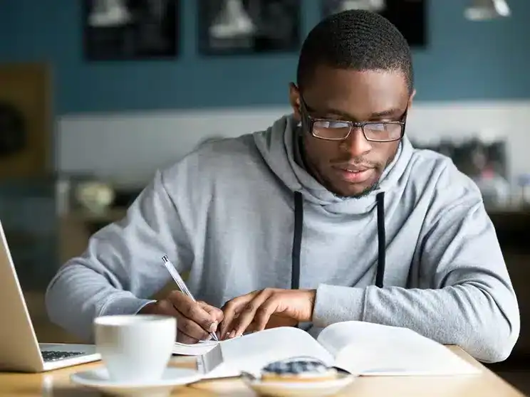 a male college student writing down notes