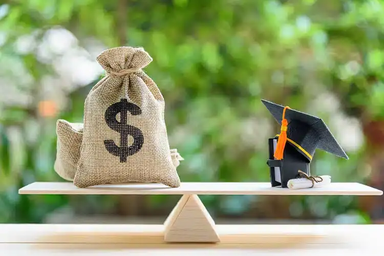 cash in a burlap bag being weight against a graduation cap