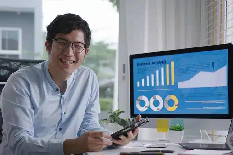 MBA Finance male student seated next to his desktop