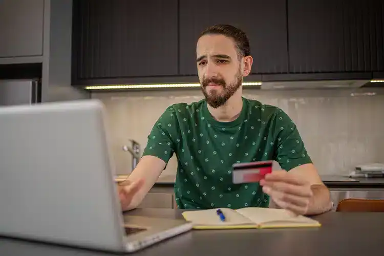 a male college student paying for online college using his laptop