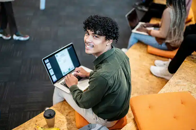 a male college student working on a college assignment on his laptop
