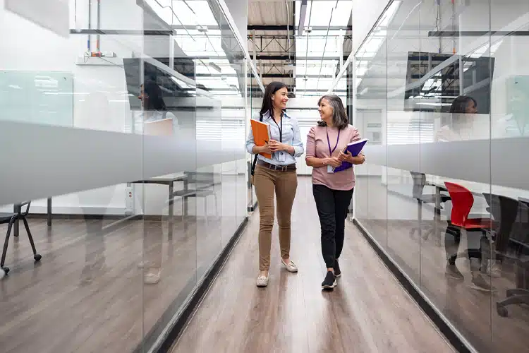 two female MBA students chatting and passing together through a hallway