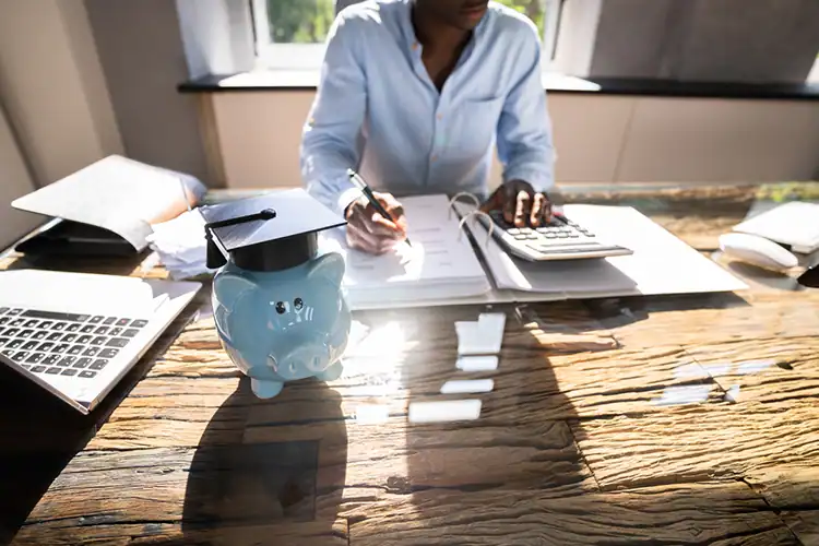 a male college student sitting at his work-desk and looking for low-cost college degrees online