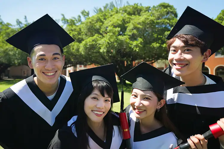 Group of diverse graduates in caps and gowns celebrating outdoors at University of the People.